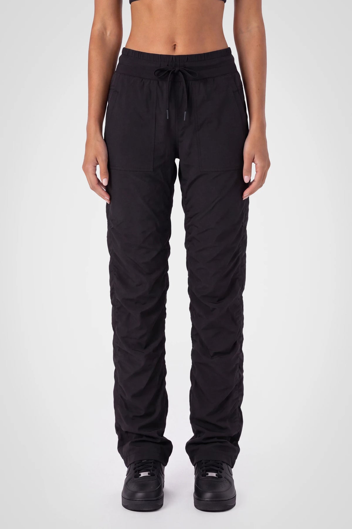 Women’s Black Adventurous Pant, front close-up showing the elastic drawstring waistband, oversized patch pockets and gathered cuffs.