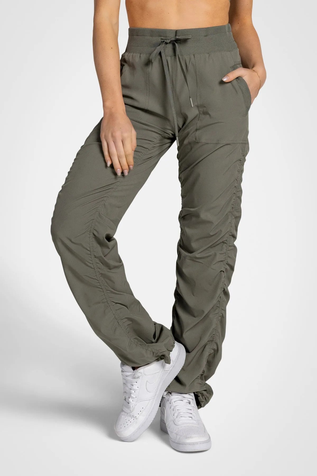 Women’s Dusty Olive Adventurous Pant, front three-quarter studio view showing the drawstring waist, patch pockets and tapered leg.