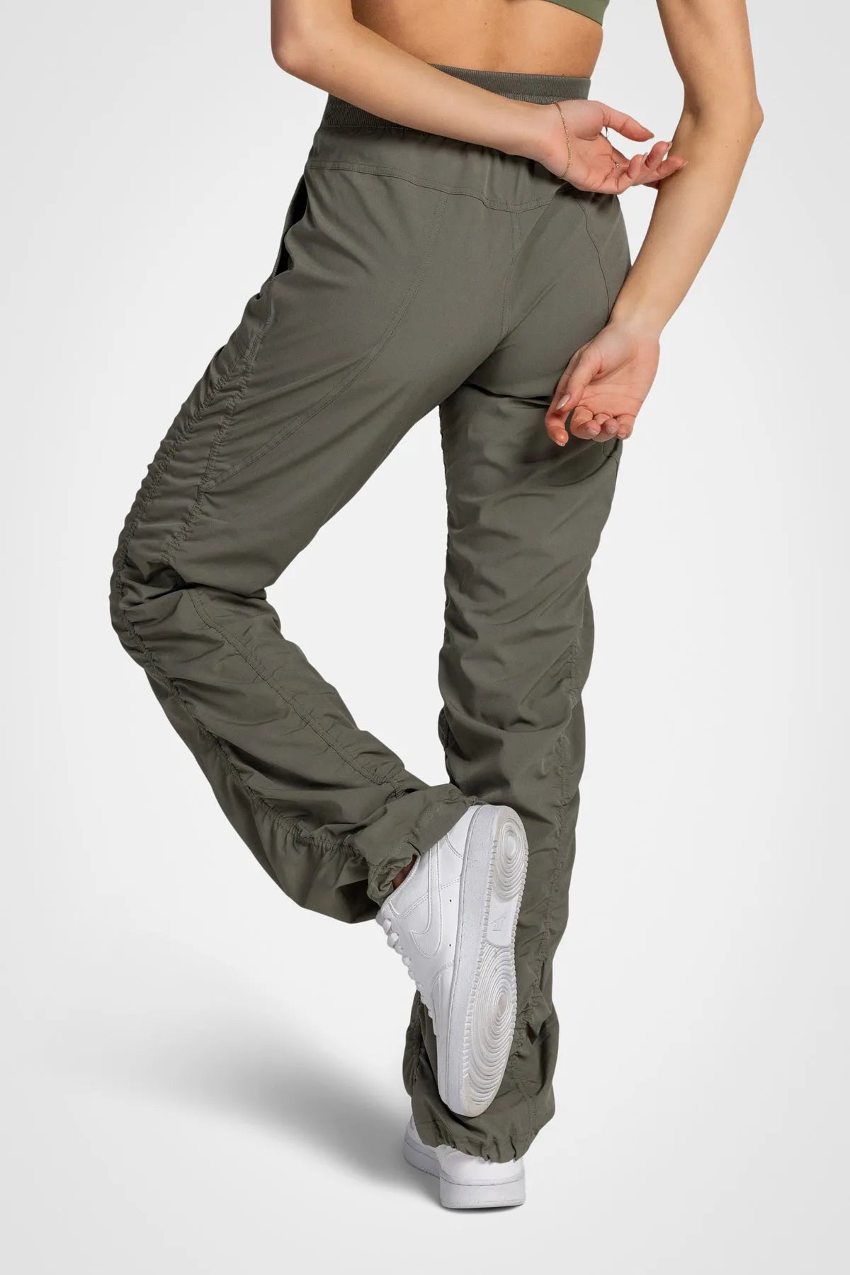 Women’s Dusty Olive Adventurous Pant, rear three-quarter studio view showing the relaxed fit through the seat and ankle.