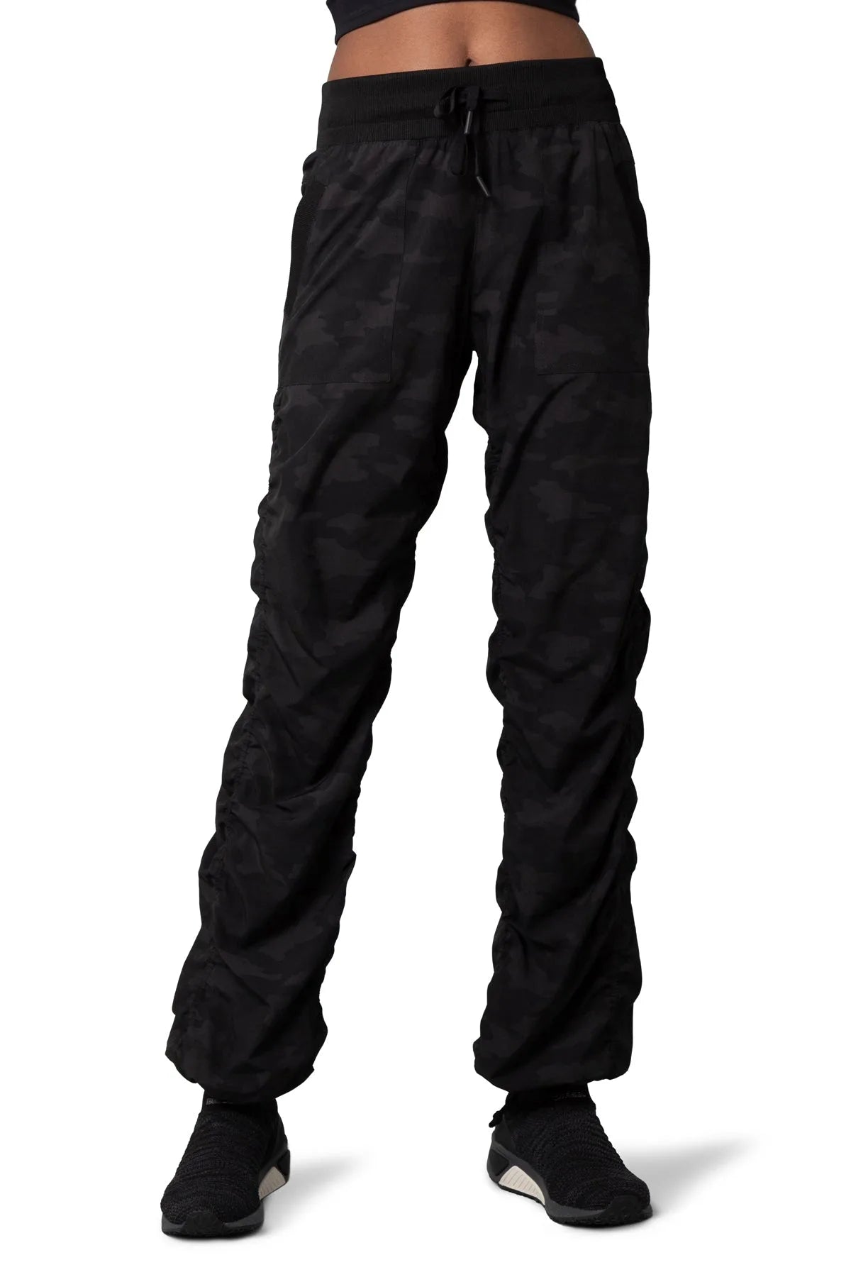 Women’s Dark camouflage print Adventurous Pant, front lower-body studio view showing the drawstring waist, patch pockets and gathered cuffs.