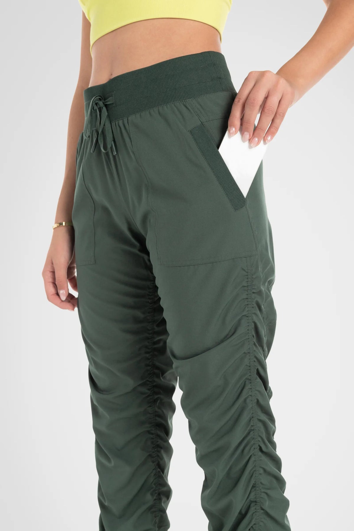 Women’s Cilantro Adventurous Pant, side studio view showing the relaxed tapered leg, utility pocket and gathered cuff.