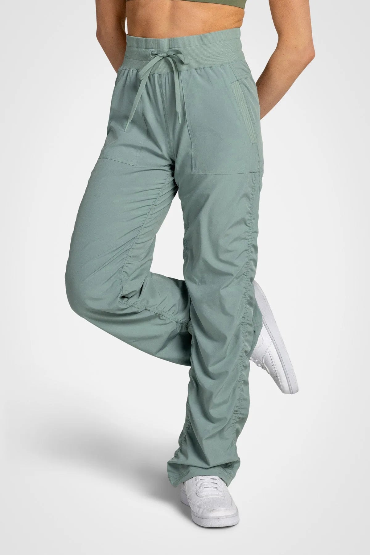 Women’s Iceberg Green Adventurous Pant, front lower-body studio view showing the elastic drawstring waist, patch pockets and gathered cuffs.