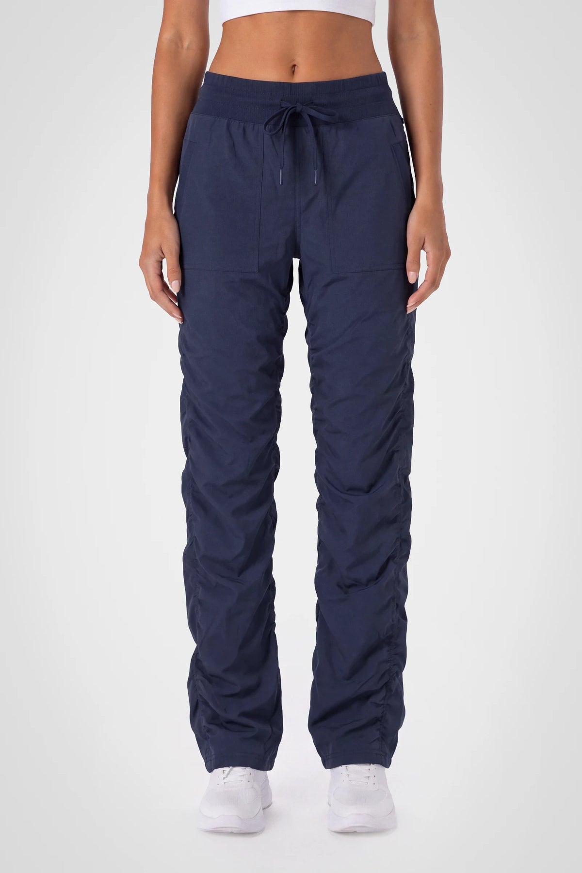 Women’s Navy Adventurous Pant, front studio view showing the elastic drawstring waist, utility patch pockets and gathered cuffs.