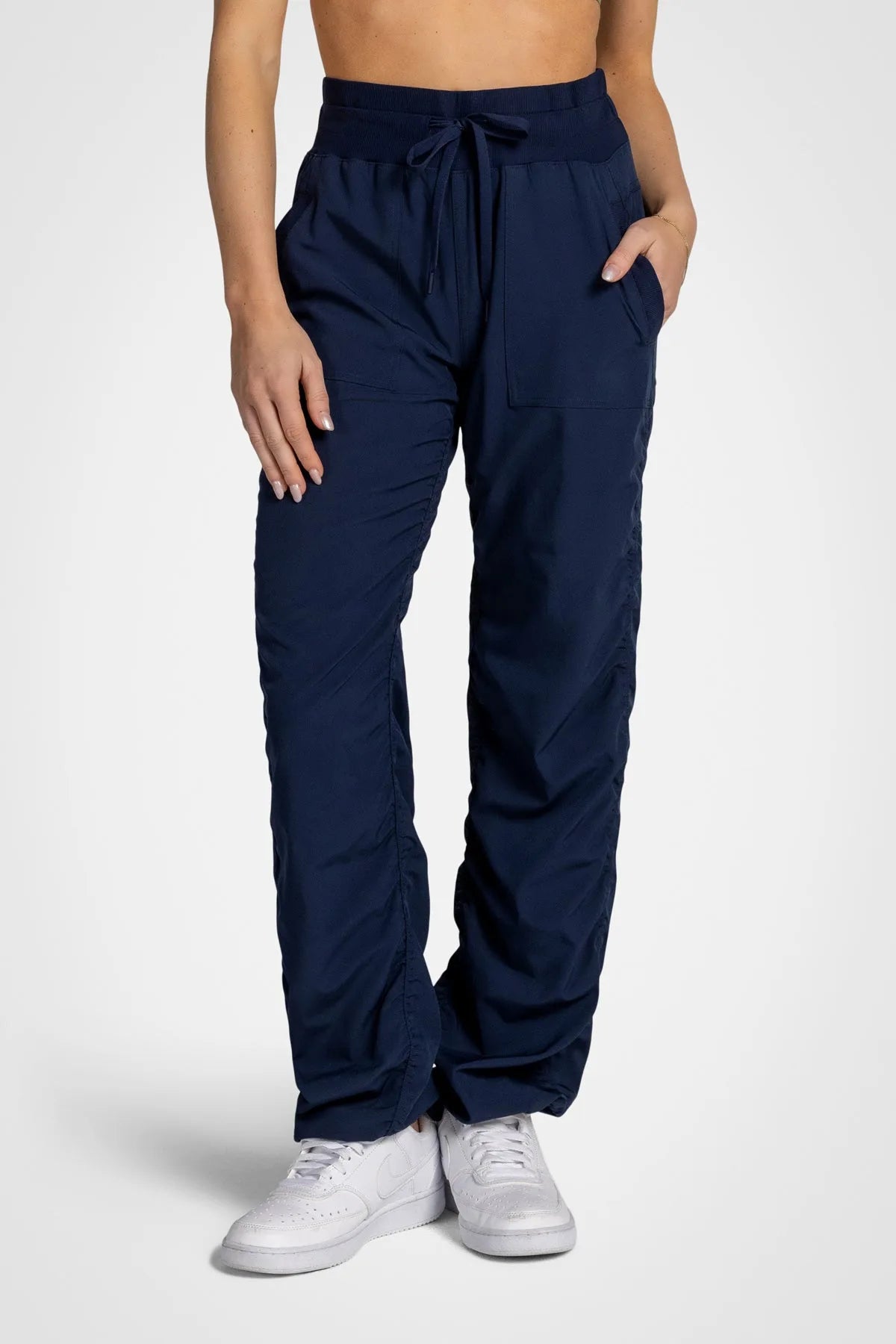 Women’s Mood Indigo Adventurous Pant, front lower-body studio view showing the elastic drawstring waist, patch pockets and gathered cuffs.