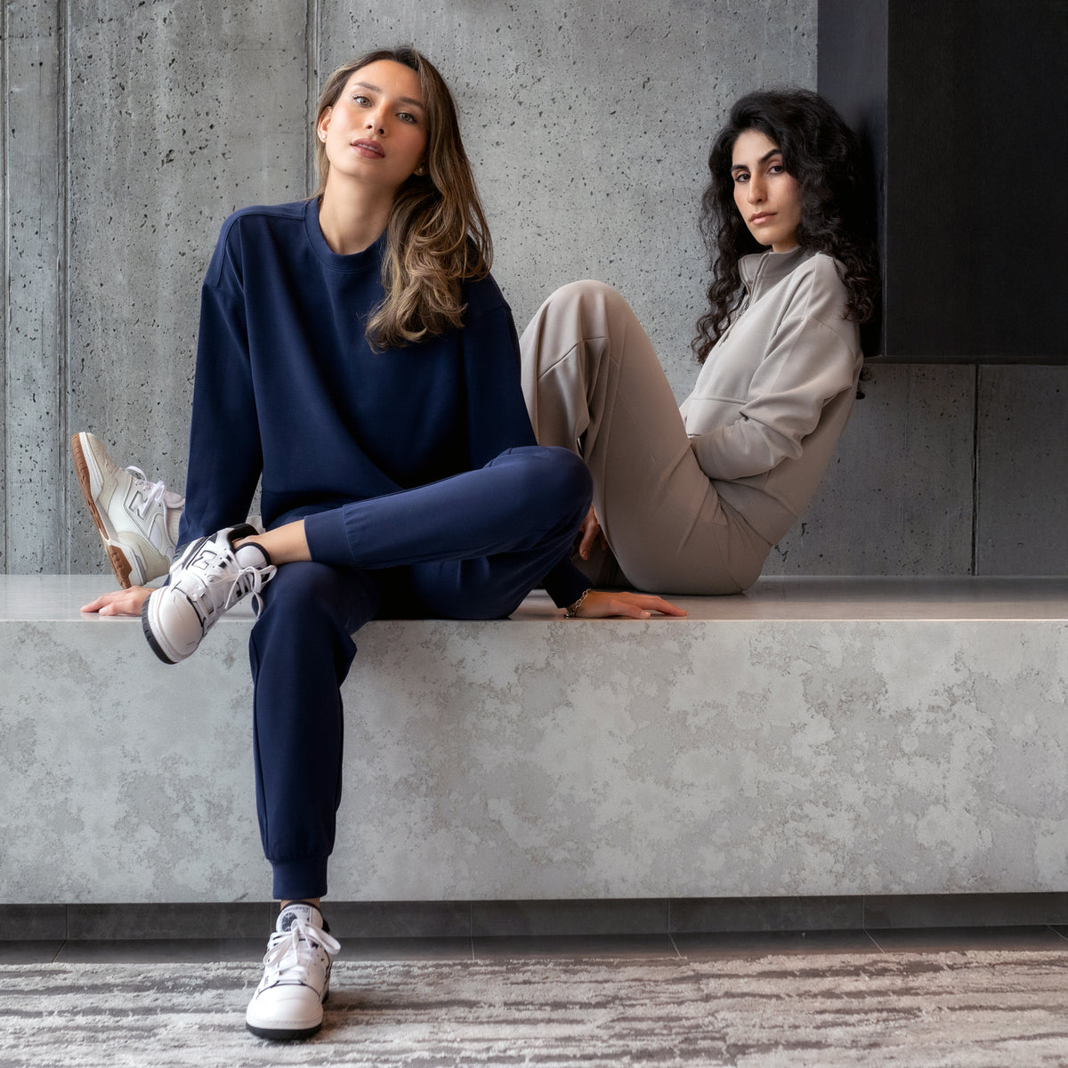 Two women sitting on a marble ledge wearing Kyodan loungewear